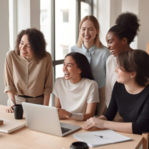 a group of diverse background women smiling around a laptop