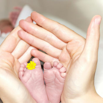 A photo of woman's hands holding baby feet.