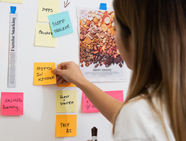 a young woman pressing sticky notes on a white board